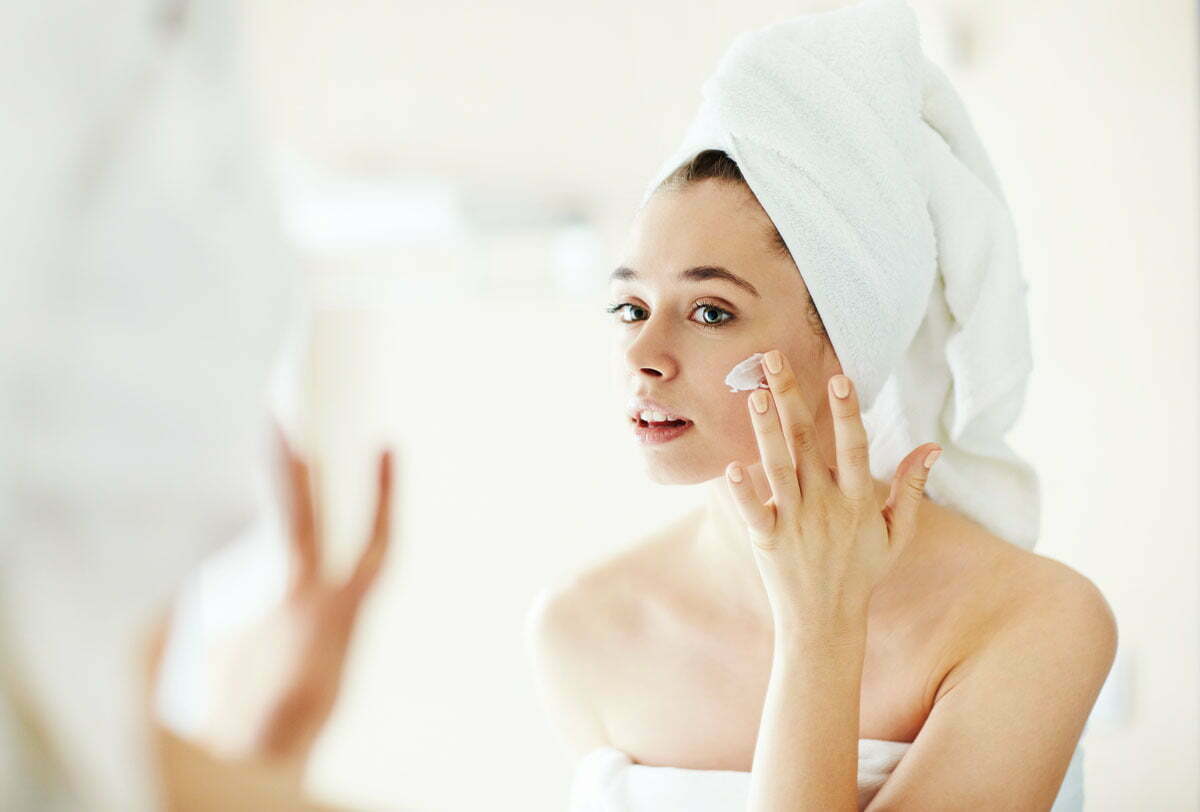 woman putting lotion on cheek