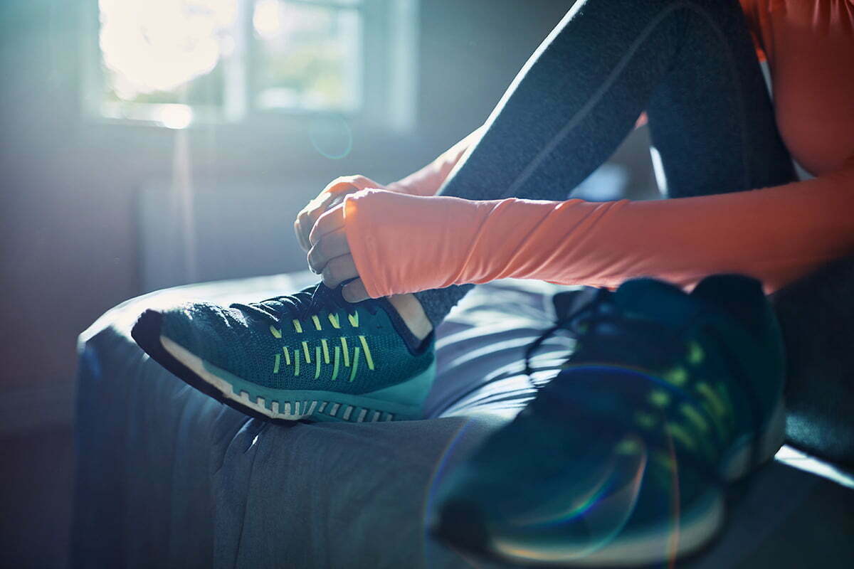 Young woman tying workout shoes