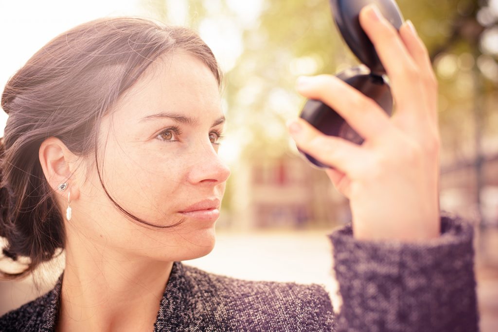 Woman check complexion in a compact mirror