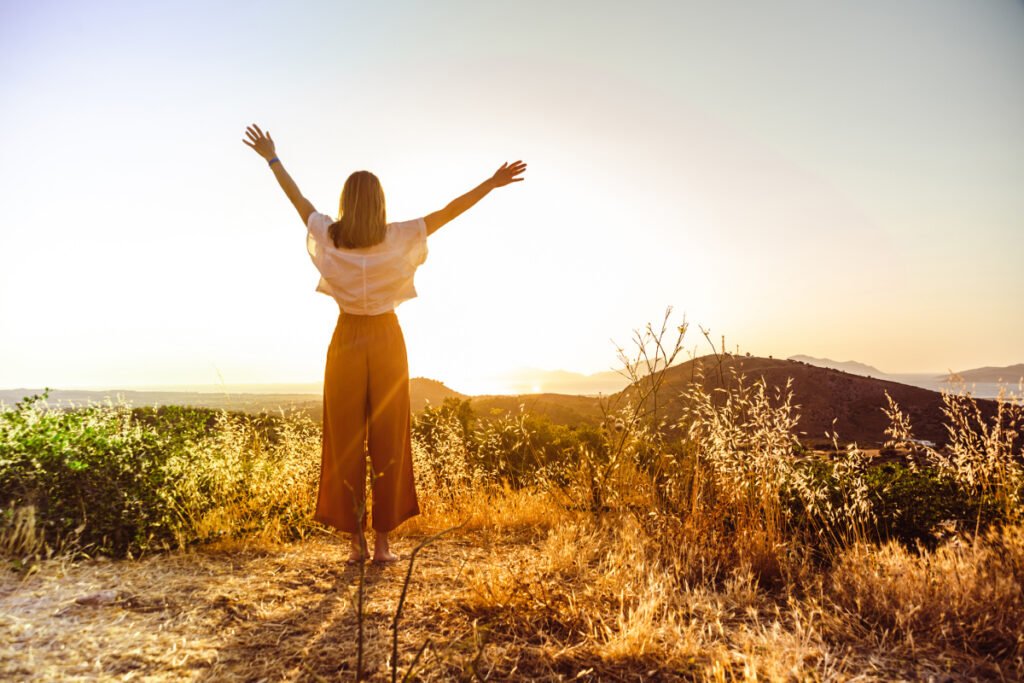 Woman raising her arms above her head outside